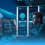 O miniatură pătrată de blog (thumbnail) care se concentrează strâns pe un tânăr specialist în automatizare AI, cu ochelari și barbă, lucrând intensiv într-un mediu tech modern și futurist. El este așezat la un birou și privește spre un monitor principal curbat care afișează un tablou de bord plin de grafice, cod de automatizare și date de proces. În spatele lui, ecrane mai mari în format portret arată o schemă a unui creier digital AI și alte analize de date complexe. Întreaga scenă este învăluită de o lumină neon albastră rece predominantă. Partea de jos a imaginii are un gradient albastru difuz, specific pentru miniaturile de blog, conceput pentru a face spațiu pentru un titlu sau text de suprapunere.